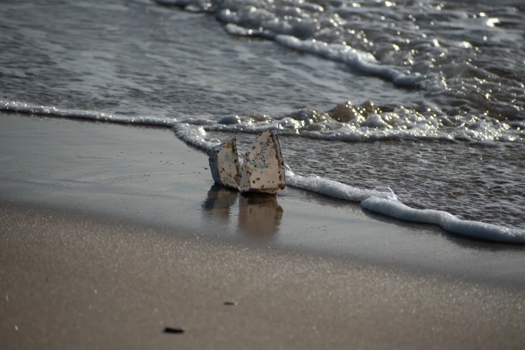 Nave di Carta sulla Spiaggia Bagnata